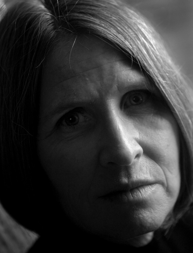 Black and white Author photo; Terra Trevor stares into the camera, the left half of her face in shadow.